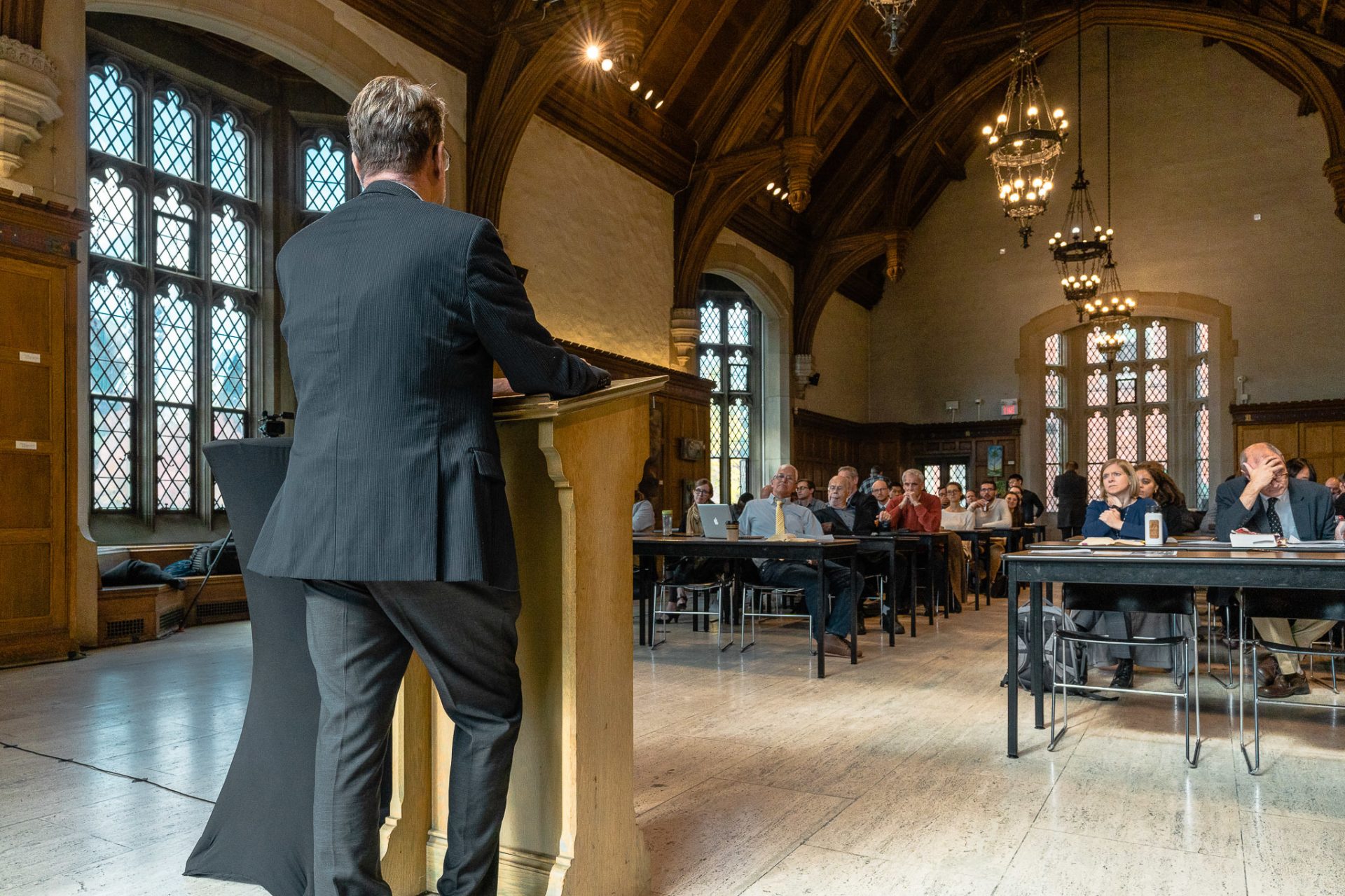 A man teaches a full house of people from behind a pulpit