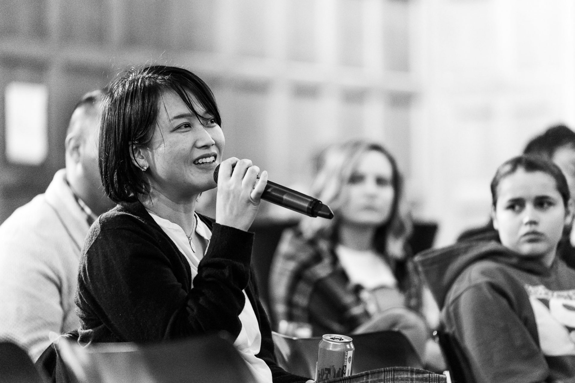 Black and white photo of a woman in an audience holding a microphone