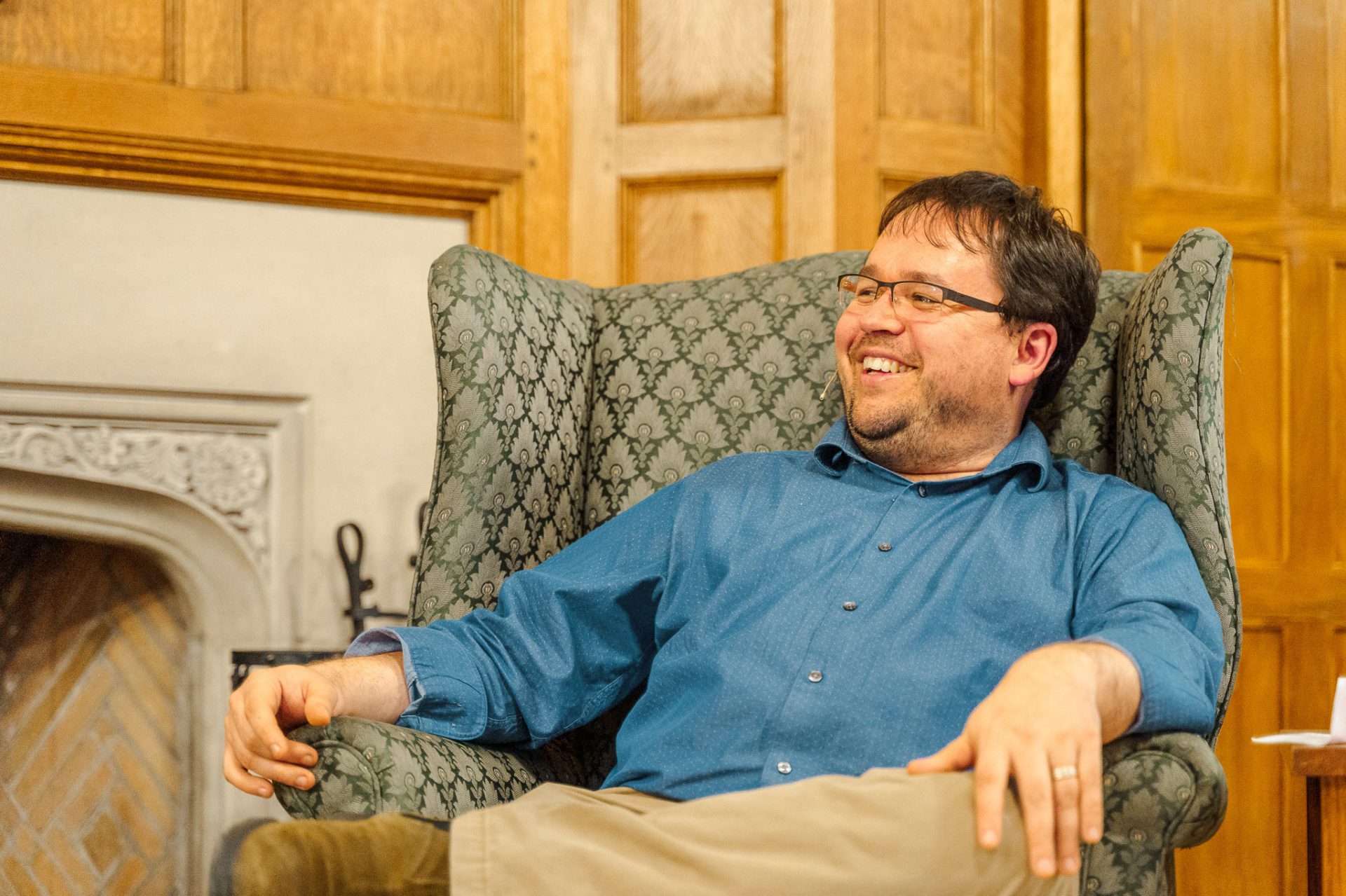 A man reclines in a sofa chair by a fire