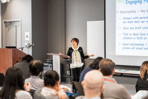 A woman teaches in a classroom behind a pulpit