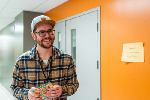 Man in hallway holding CD and smiling