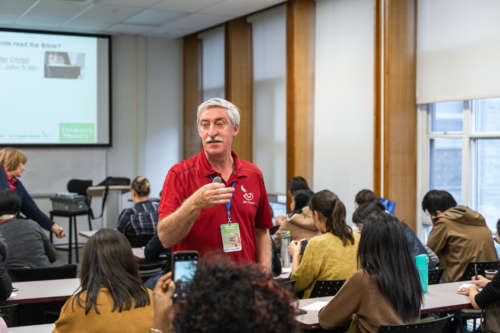 A teacher walks down the row of his classroom