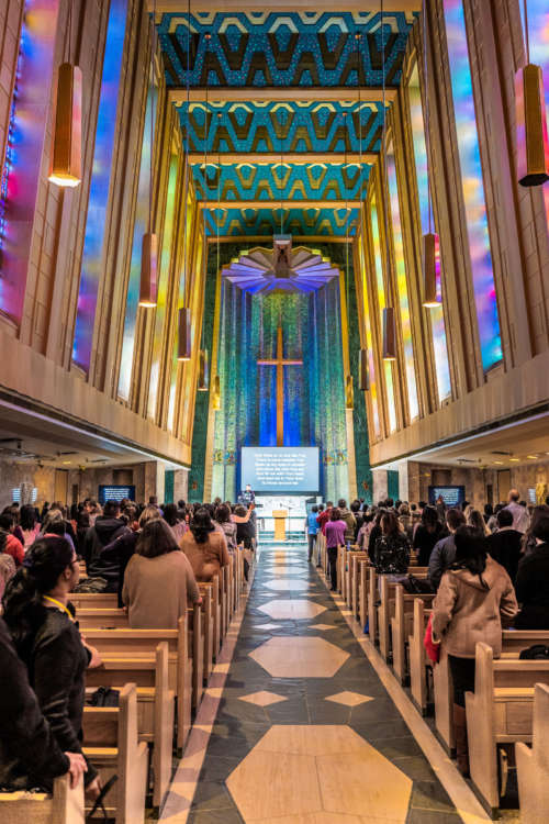 Light pours through stained glass windows in a chapel during mid-day